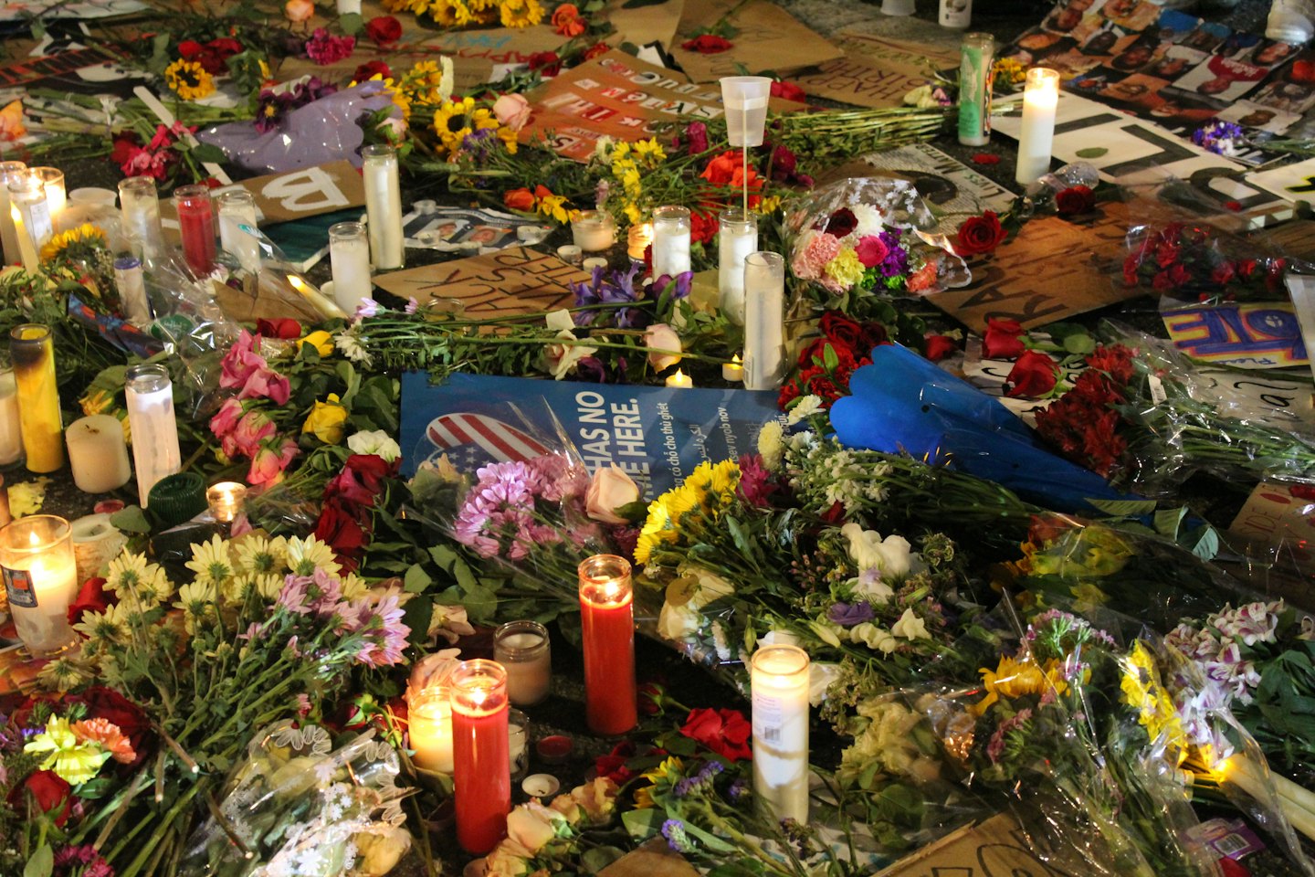 Candele accese e bouquet floreali a un memoriale di strada.